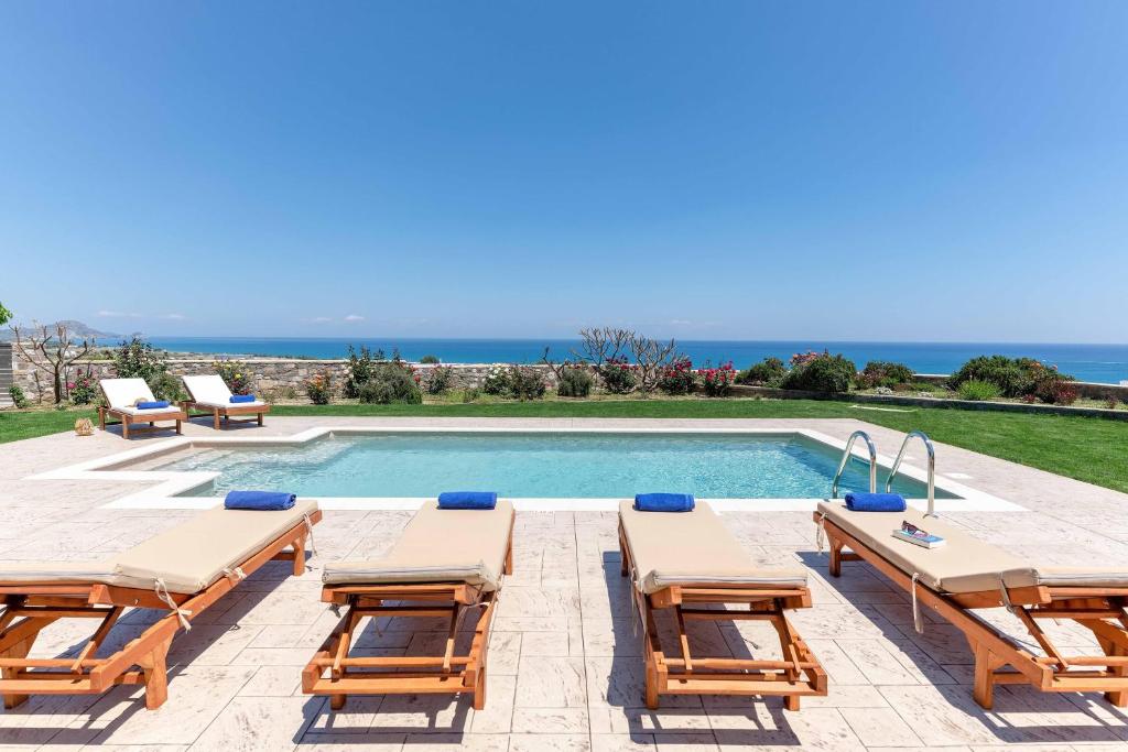 a swimming pool with chaise lounge chairs and a villa at Majestic View Villa in Kolimbia