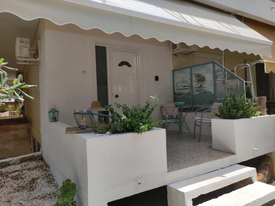 een huis met een veranda met twee potplanten erop bij Όμορφο διαμέρισμα με μπαλκόνι στη Σαρωνίδα in Saronida