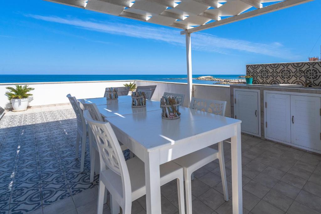 una mesa blanca y sillas en un patio con vistas al océano en La fuga blu di Marzamemi, en Marzamemi