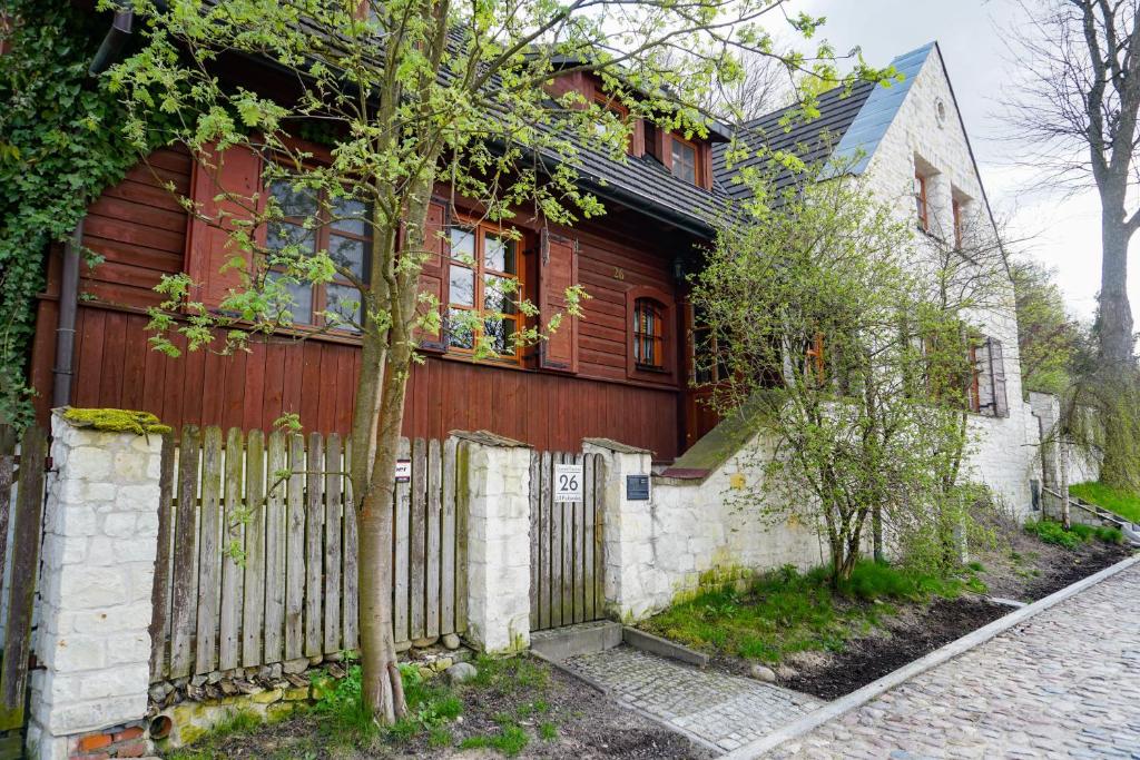 ein Holzhaus mit einem Zaun und einem Baum in der Unterkunft Domek Prezesa in Kazimierz Dolny