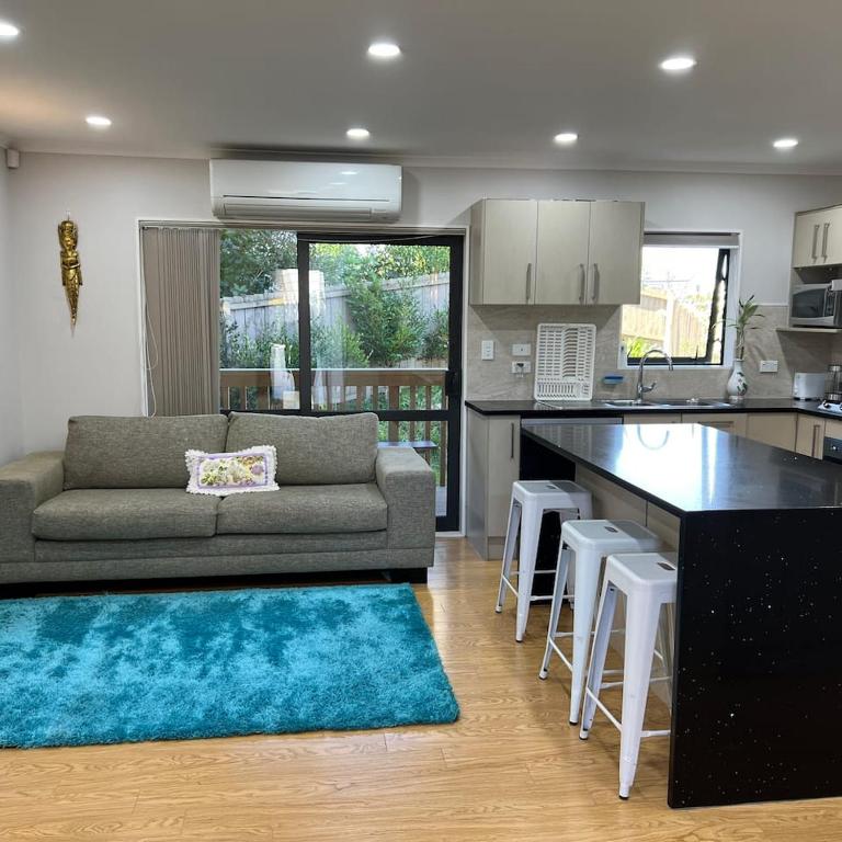 a kitchen and a living room with a couch and a table at Beautiful 2 Bedroom Home in Auckland