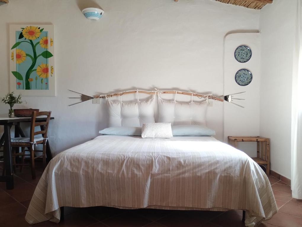 1 dormitorio con cama blanca y cabecero de madera en La Casetta, en Padru