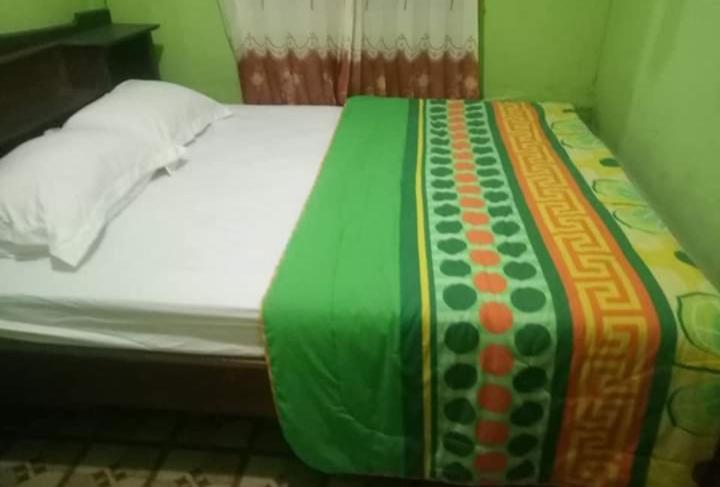 a bed with a green and orange blanket on it at WATURAKA TOURISM VILLAGE in Ende