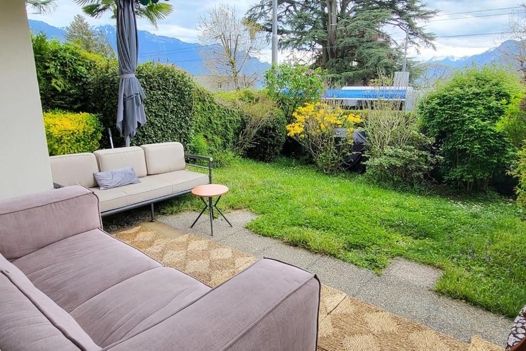 een woonkamer met een bank en een groene tuin bij Lake side(5min)/fire place/garden/freeparking/45m2 in La Tour-de-Peilz