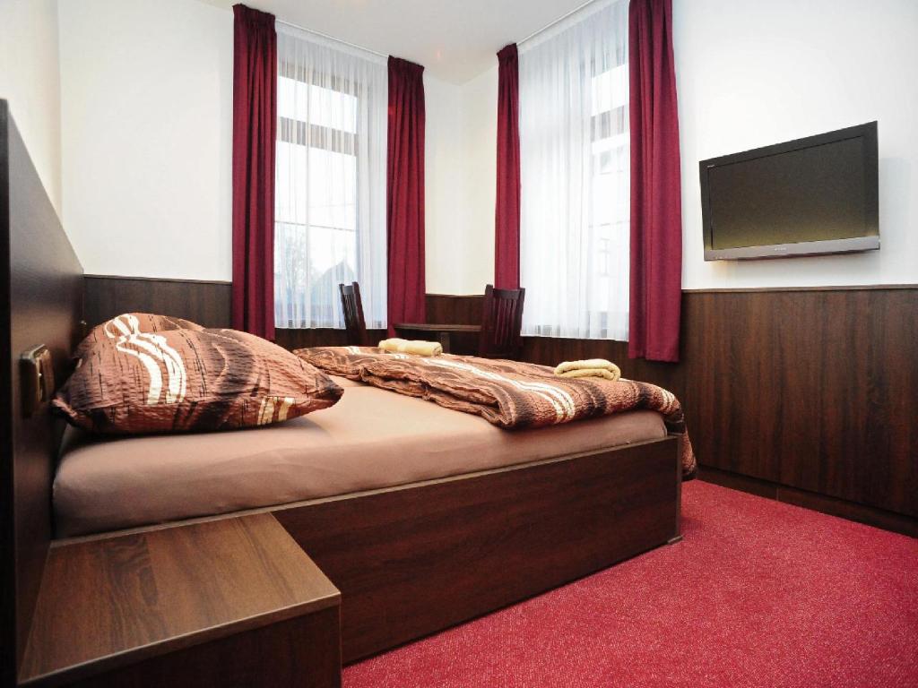 a bedroom with a bed with red curtains and a flat screen tv at Penzion Budopartner in Jívka
