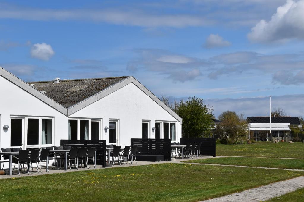 a white building with tables and chairs in a field at Kerteminde Byferie - Hyrdevej 83 - 85J in Kerteminde