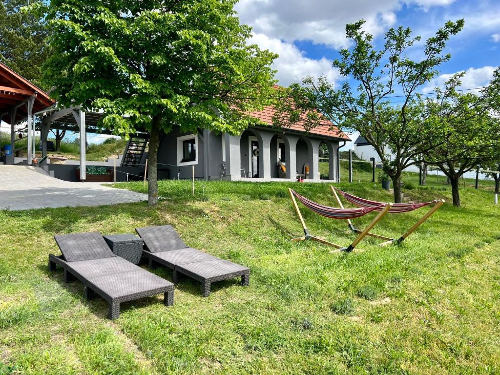 a yard with two benches and a hammock and a house at Völgyhíd Village Balaton in Kőröshegy