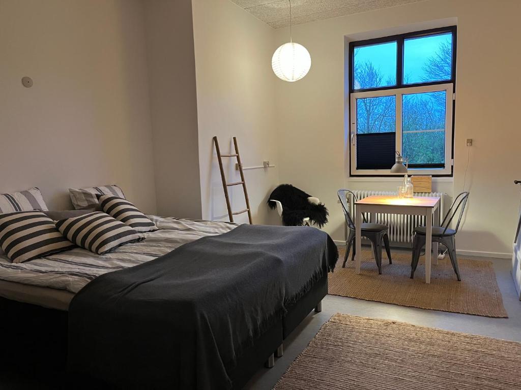 una camera con letto, tavolo e sedia di Room 4 - Hawkraft kulturhotel a Vestervig