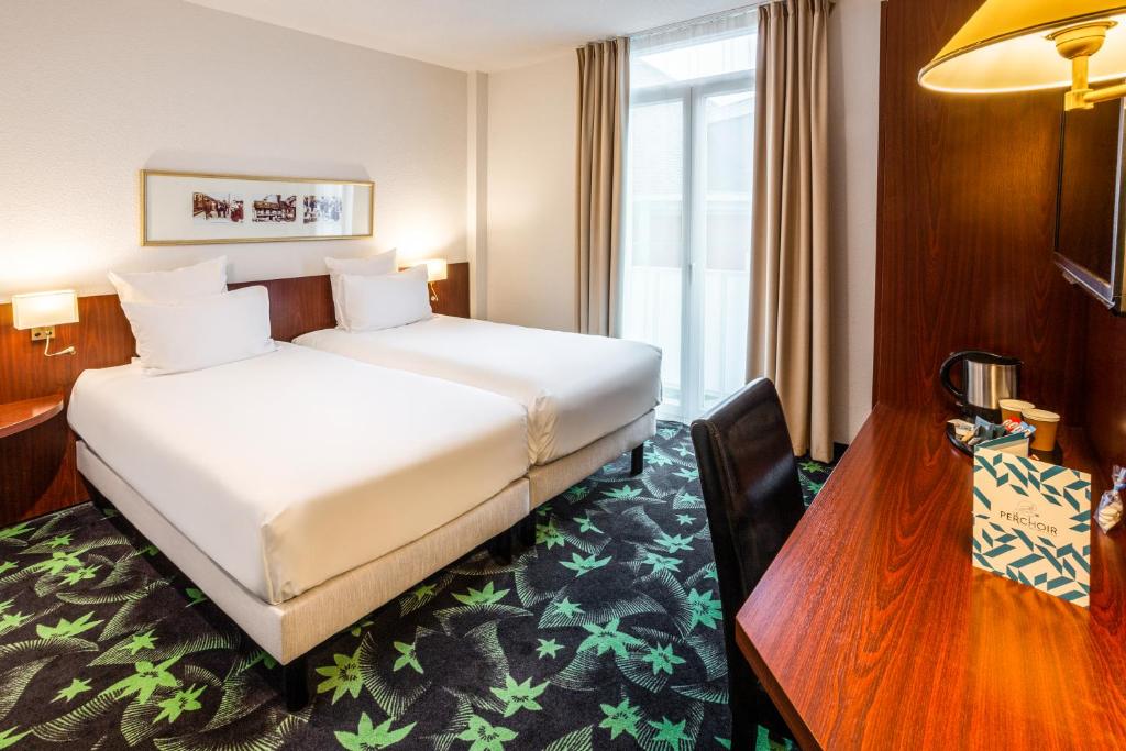 ルルドにあるメルキュール ルルド アンペリアルのベッドとデスクが備わるホテルルームです。