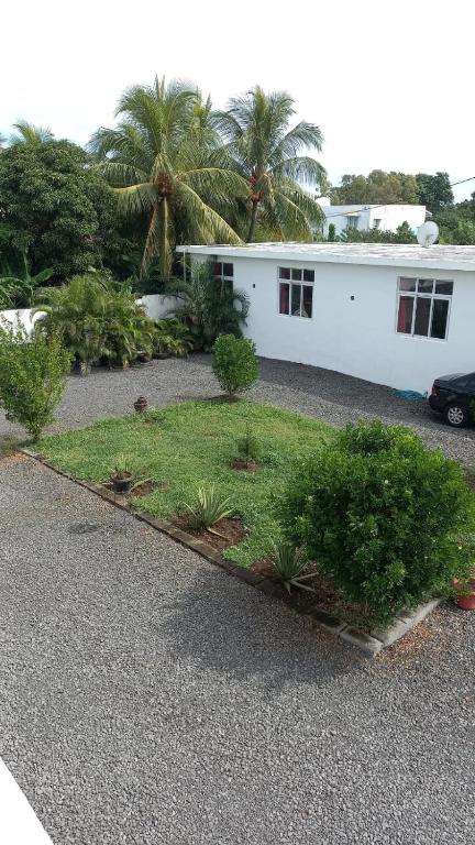 een wit huis met palmbomen op een parkeerplaats bij Loft Crécerelles in Pereybere