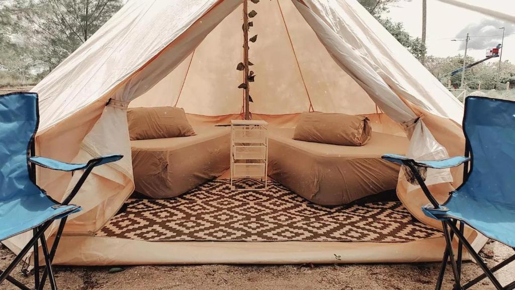 tenda con 2 sedie e un letto. di Rustika Glamping a Kampong Tanjong Che Lahom