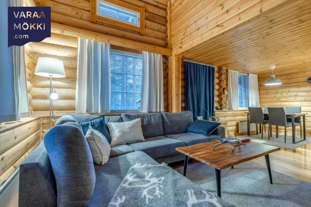 a living room with a blue couch and a table at Alppirinne - Tunnelmallinen loma-asunto Suomulla in Suomutunturi