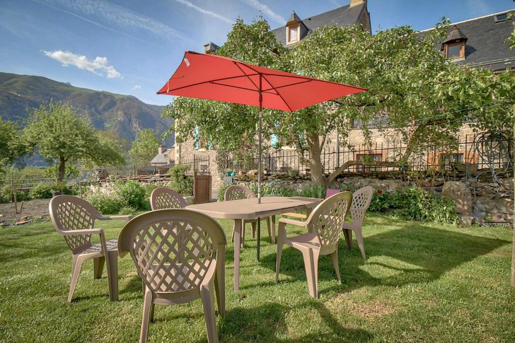 a table and chairs with a red umbrella at Location À 5mn De Saint Lary in Sailhan