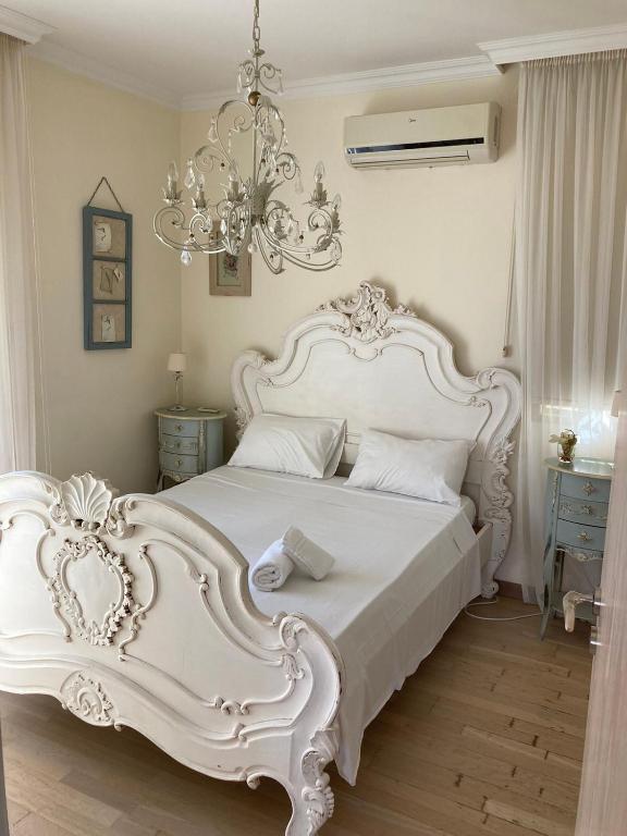 a white bed in a bedroom with a chandelier at Anna Villa in Protaras