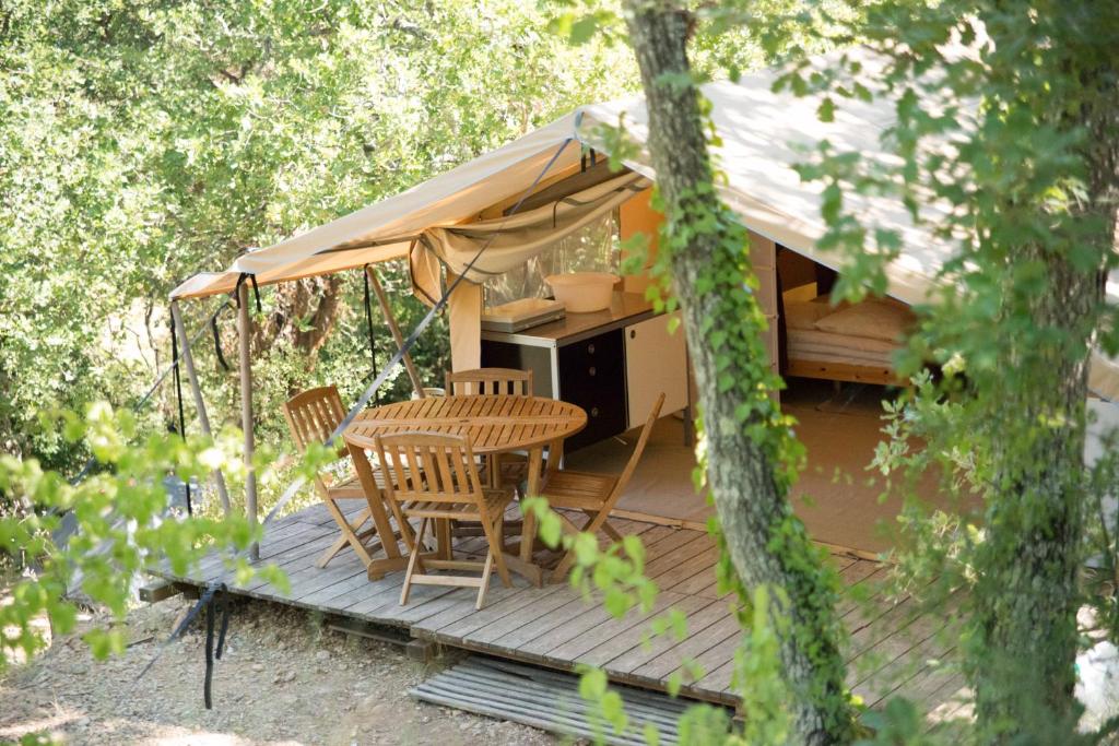 a cabin with a table and chairs on a deck at Camping la Grangeonne in Esparron-de-Verdon