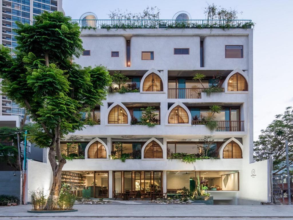 een appartementencomplex met een boom ervoor bij Le Bouton Smart Boutique Hotel in Da Nang