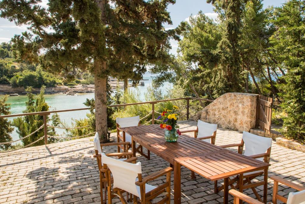 a wooden table and chairs on a patio with a river at Grand Bleu Porto Heli - Beachfront House, Agios Emilianos in Porto Heli