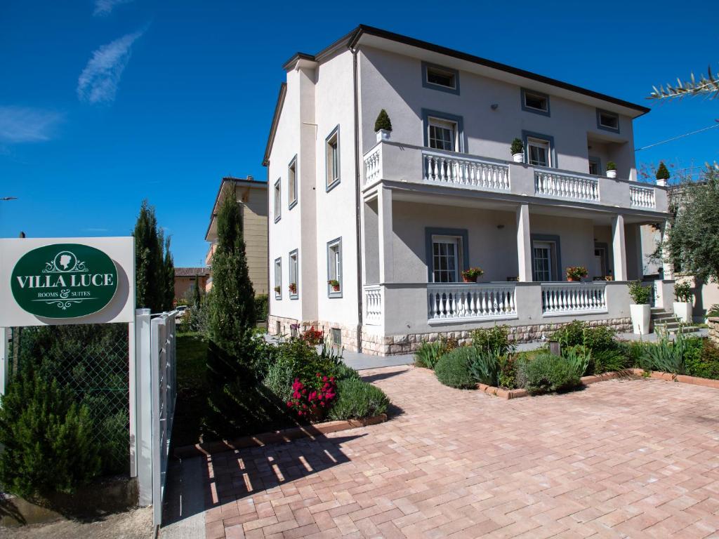 Villa Luce Assisi Rooms & Suites في سانتا ماريا ديجلي آنجيلي: البيت الأبيض مع وجود علامة أمامه