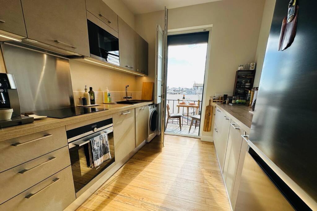 a kitchen with stainless steel appliances and a wooden floor at Panorama des Chartrons in Bordeaux