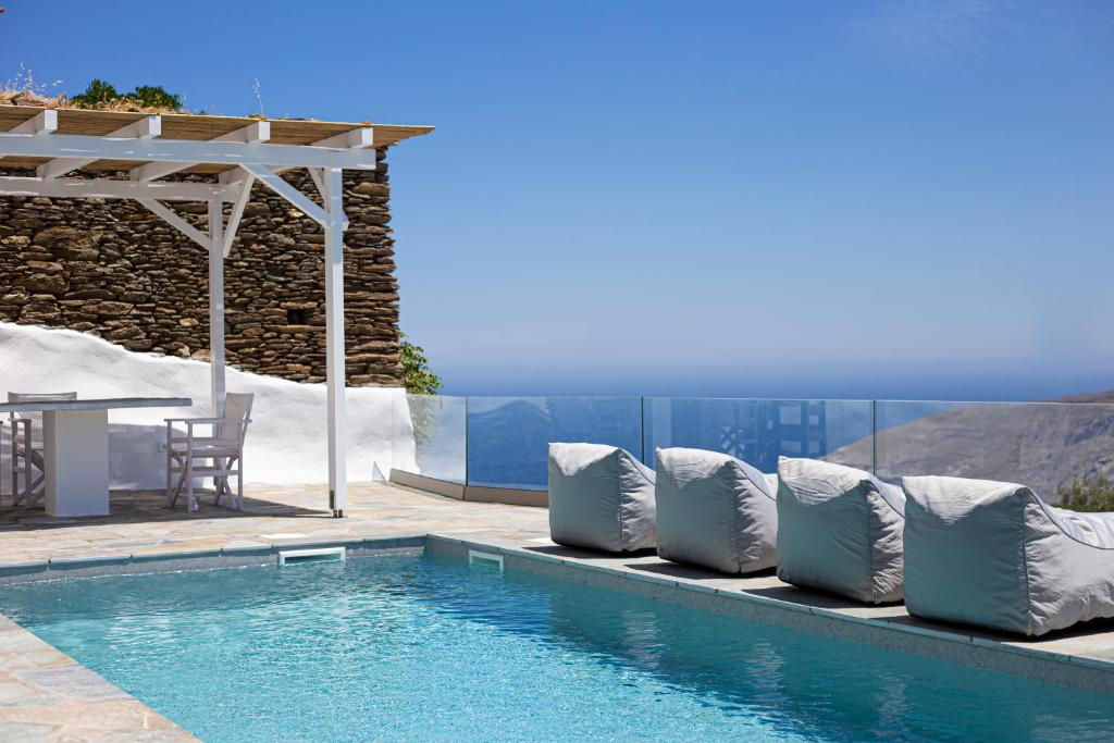 einen Pool mit Kissen neben einem Tisch und eine Terrasse in der Unterkunft Villa Stefano La Fleur Andros in Ándros