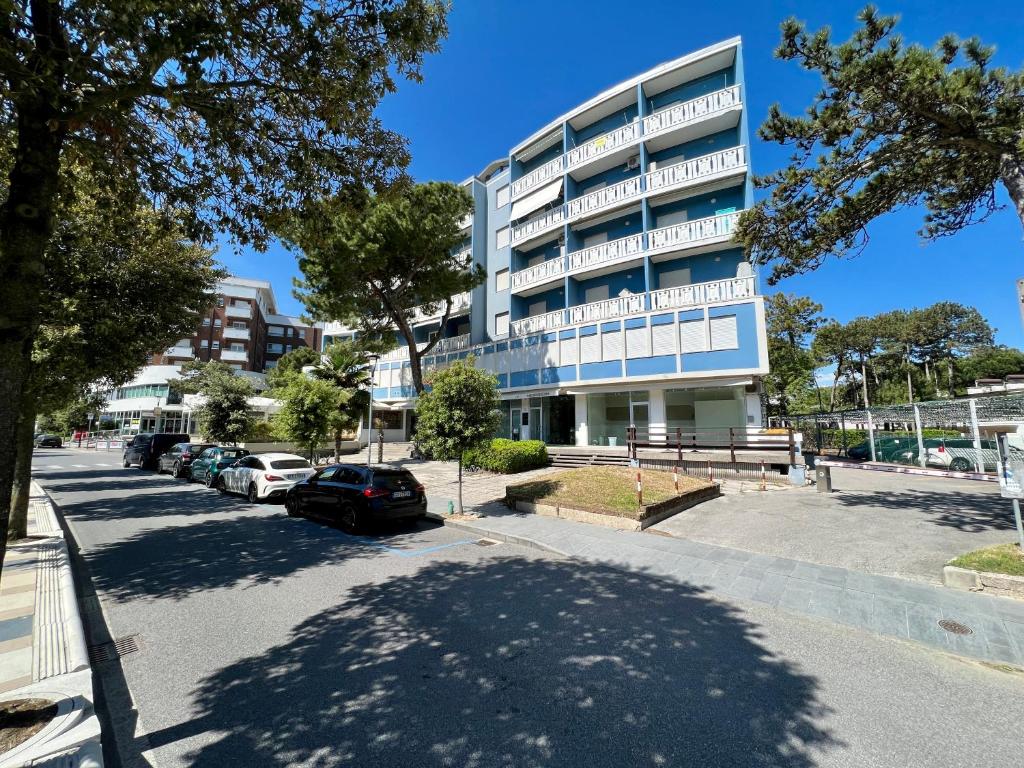 a building with cars parked in a parking lot at Condominio Sporting in Lignano Sabbiadoro