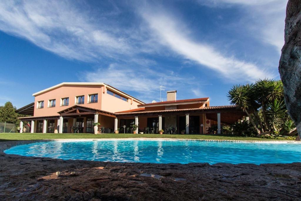 una casa con piscina frente a ella en Agriturismo Villa Gaia, en Cabras