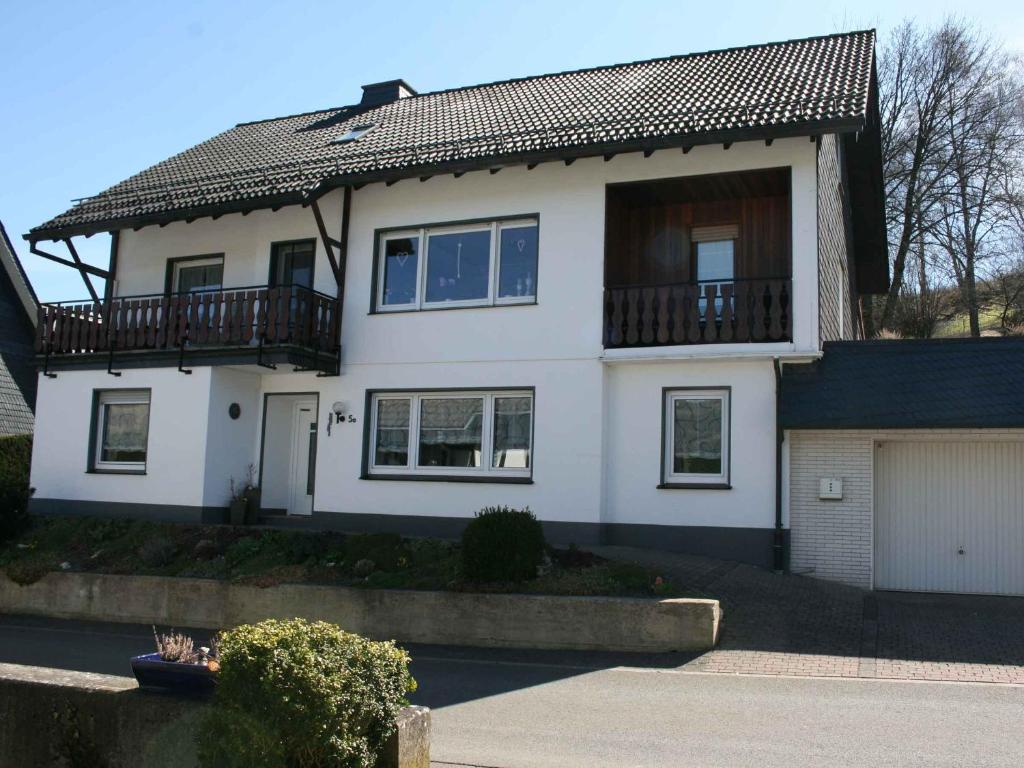 Cette maison blanche dispose d'un balcon et d'un garage. dans l'établissement Ferienwohnung Christel, à Schmallenberg