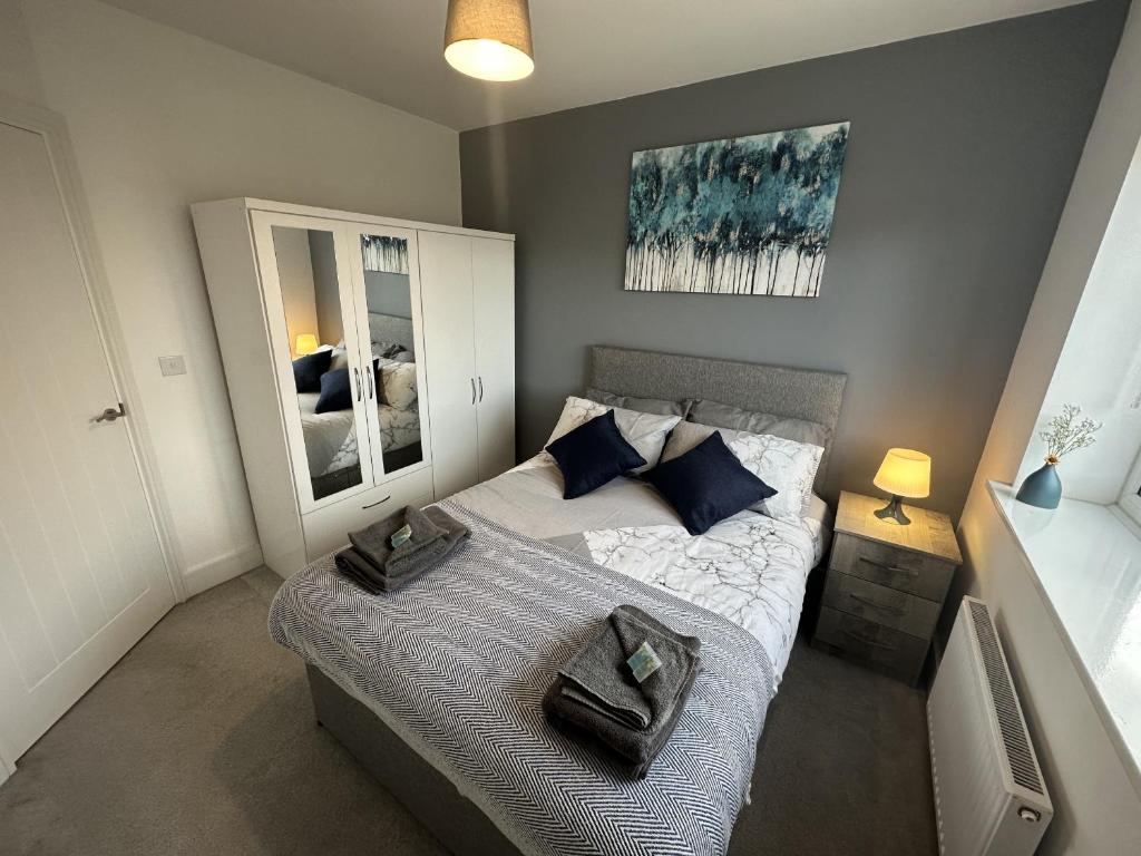 a bedroom with a bed with blue pillows and a mirror at 3 Bed Home for Contractors & Relocators with Parking, Garden & WiFi 5 mins walk to Town Centre & Train Station in Stafford
