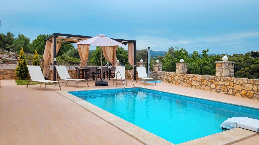 - Piscina con sillas, mesa y sombrilla en Natural view villa with private pool, en Skouloúfia