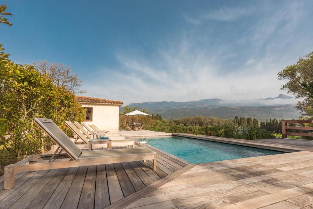a villa with a swimming pool and a deck with chairs at Casa di Pruno in Figari