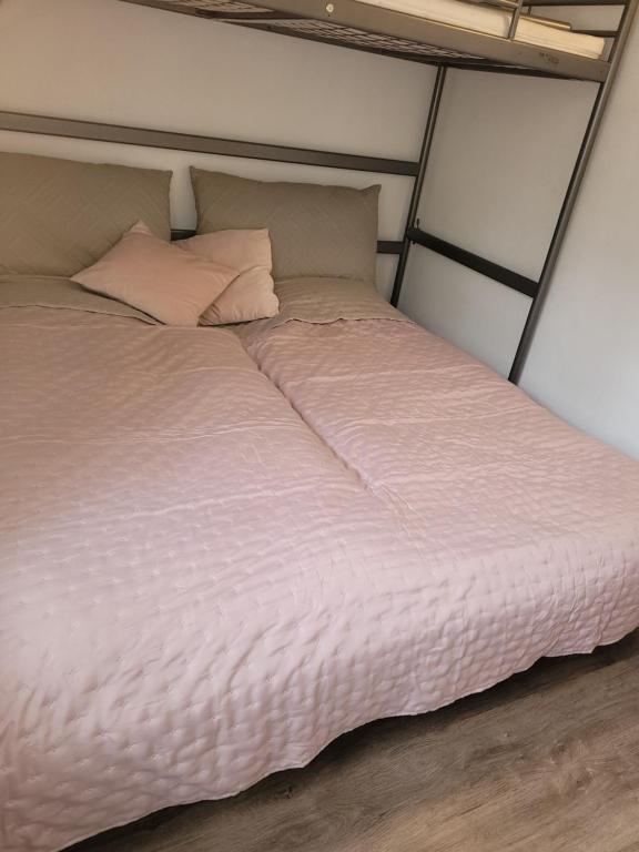 uma cama com lençóis brancos e almofadas num quarto em Skovlund Apartments em Bredsten