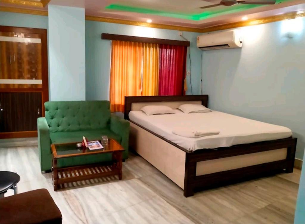 een slaapkamer met een bed en een groene stoel bij STAYMAKER Moon Light in Calcutta
