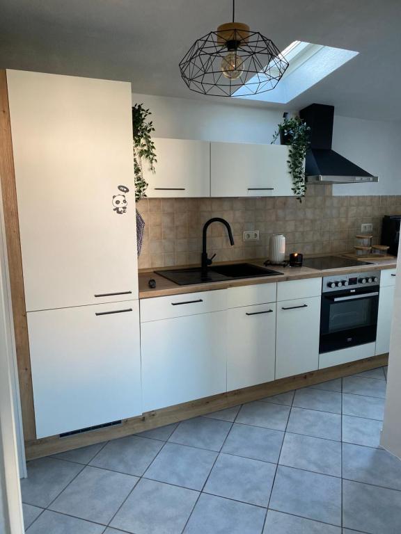 eine Küche mit weißen Schränken und einer Spüle in der Unterkunft Ferienhäuschen Gartenblick in Friedrichroda