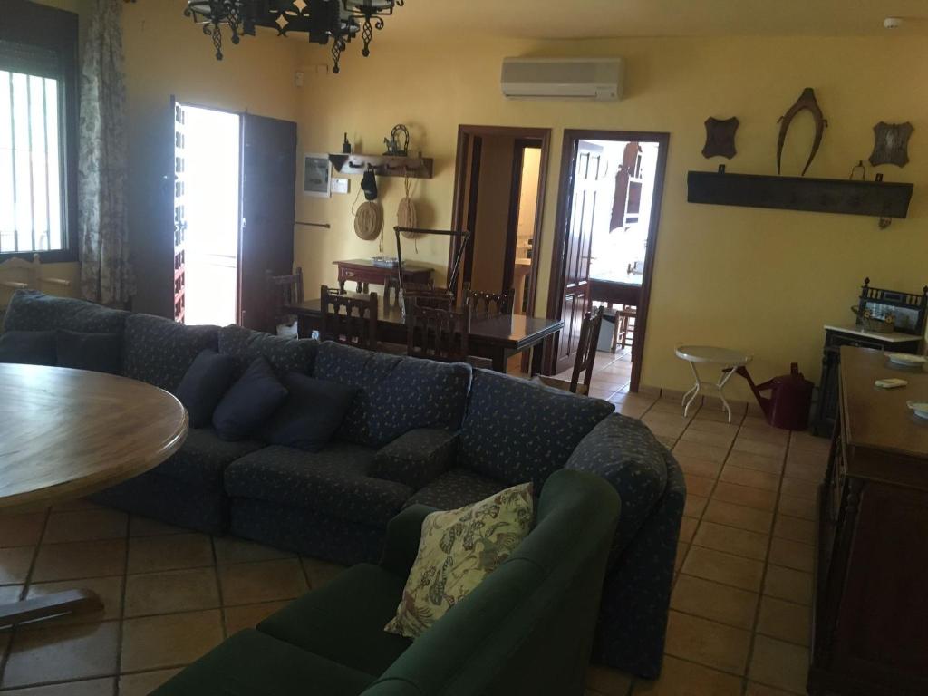 uma sala de estar com um sofá azul e uma mesa em Cortijo de Lorente Alojamiento Turístico Rural -Teba -Malaga em Teba