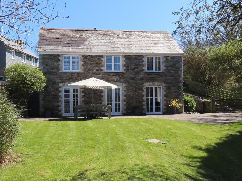 a large stone house with an umbrella in the yard at Barn Cottage in Saint Mawgan