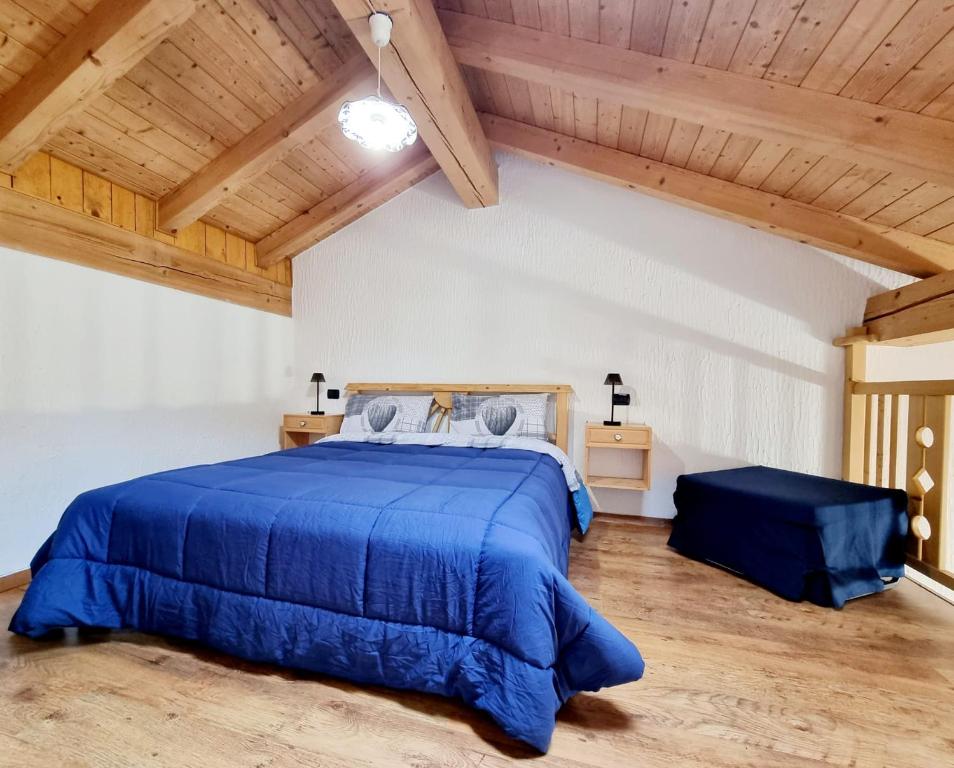 Schlafzimmer mit blauem Bett und Holzdecken in der Unterkunft Appartamento Adamello 15 in Pinzolo