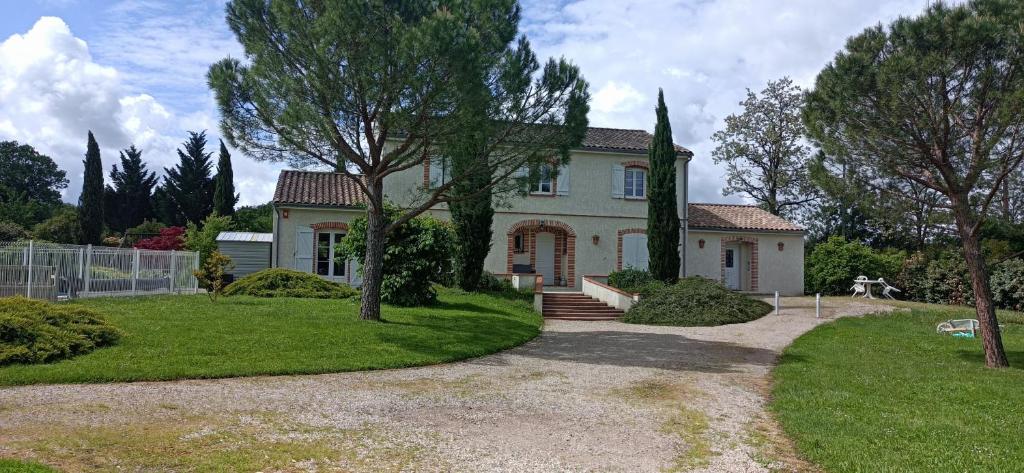 una gran casa blanca con árboles delante de ella en Logement, classé 3 étoiles, de 42 m2 tout confort avec piscine pour un couple, en Cahuzac-sur-Vère