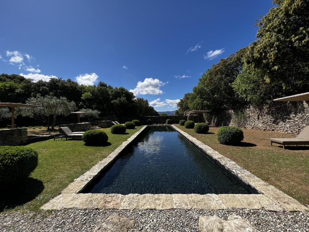a swimming pool in the middle of a garden at Le Mas de Béthel in Gordes
