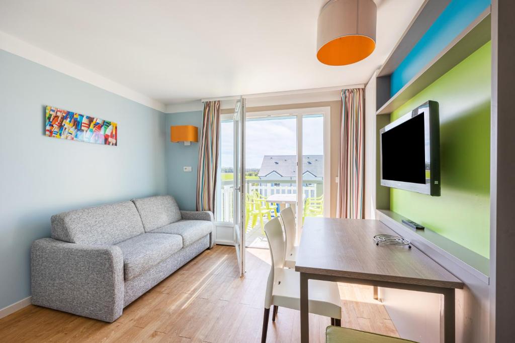 ein Wohnzimmer mit einer Couch und einem Tisch und einem Fernseher in der Unterkunft Némo - Appartement avec Terrasse in Courseulles-sur-Mer
