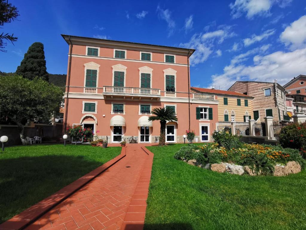 un gran edificio rosa con una pasarela de ladrillo en Albergo MP Noli, en Noli