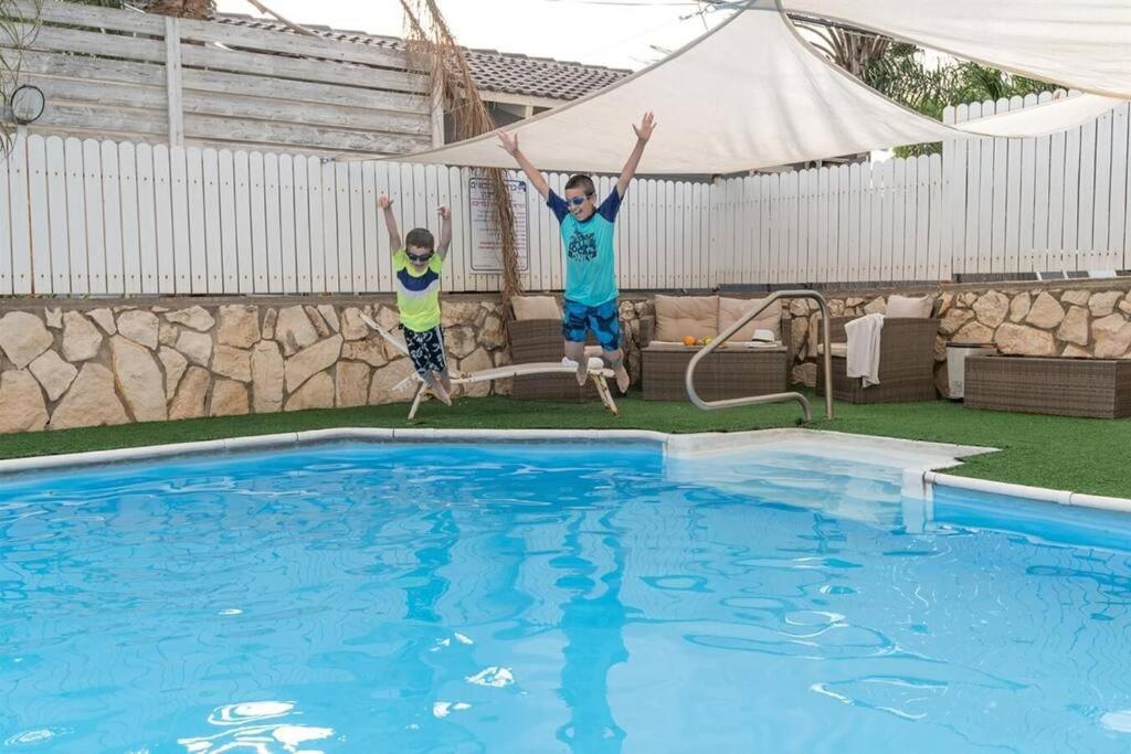 two boys jumping in the air above a swimming pool at נווה שחר - יחידת נופש עם ג'קוזי פרטי ובריכה משותפת באזור כפרי ליד טבריה in Poriyya