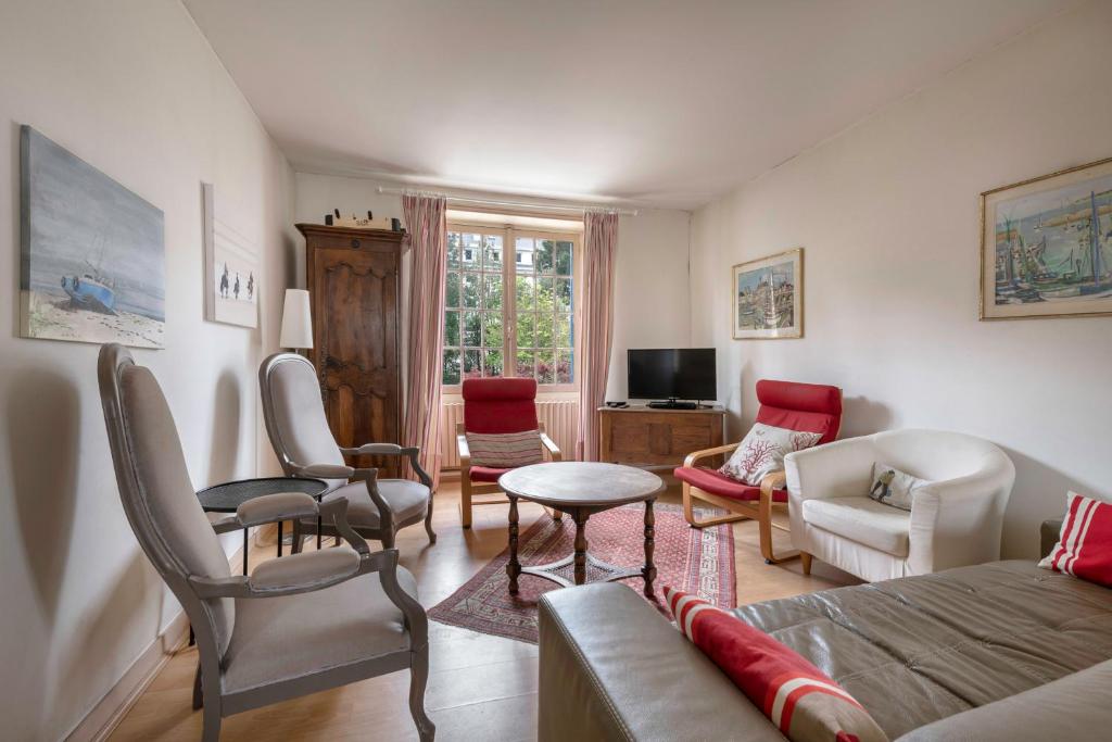 Una sala de estar con un sofá y sillas y un televisor. en Échappée familiale à deux pas de la plage, en Le Pouliguen