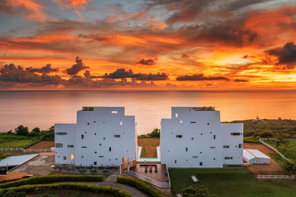 dos edificios blancos con una puesta de sol en el fondo en Kenting Ocean Paradise Resort, en Hengchun