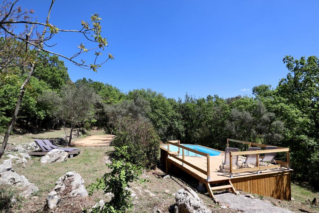 a wooden deck with a swimming pool in the woods at Le Mas des Rouquets - avec piscine et jardin in Anduze