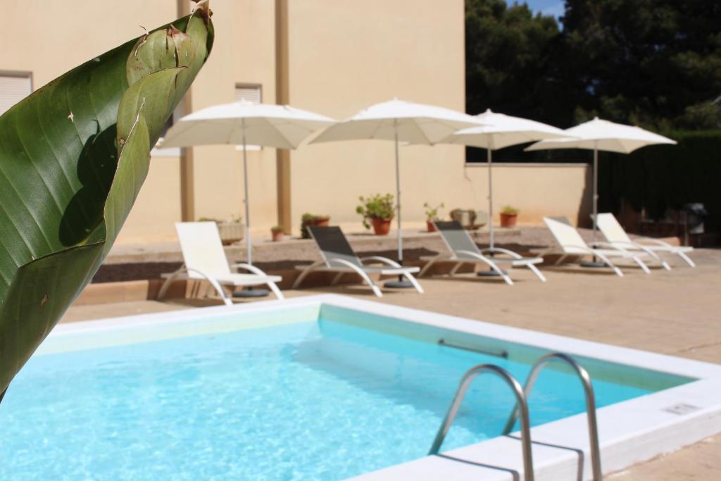 a swimming pool with chairs and umbrellas at Bluewater Hotel in Colònia de Sant Jordi