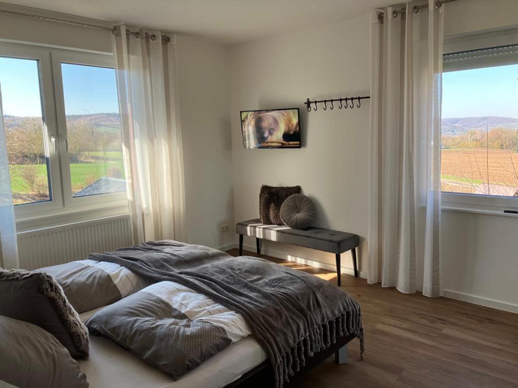 a bedroom with a bed and a table and windows at Ferienwohnungen auf dem Erlenhof in Beverungen