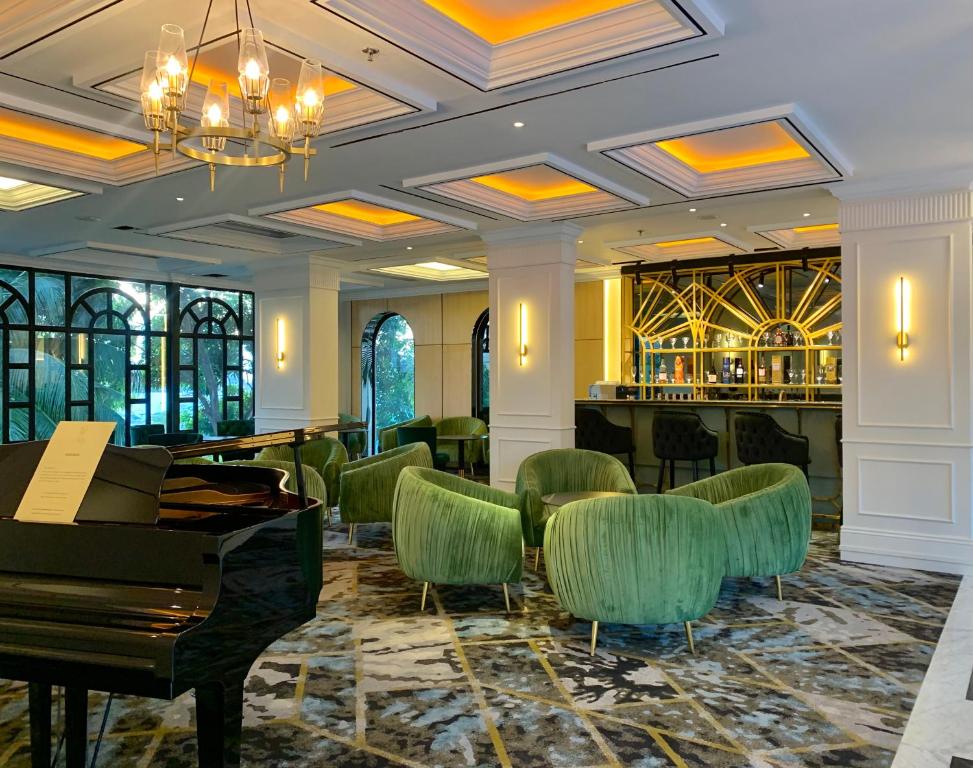 a lobby with a piano and green chairs at Grand Eska Hotel & Suites Batam in Nagoya