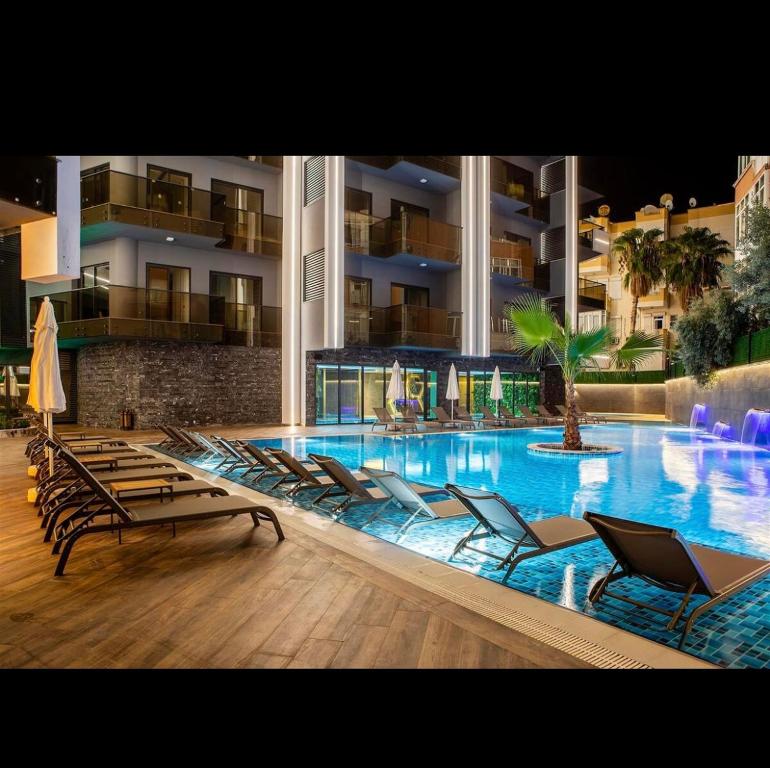 a large swimming pool with lounge chairs in a building at Lux Apartment C-LOUNGE CLEOPATRA, Cleopatra beach Alanya in Alanya