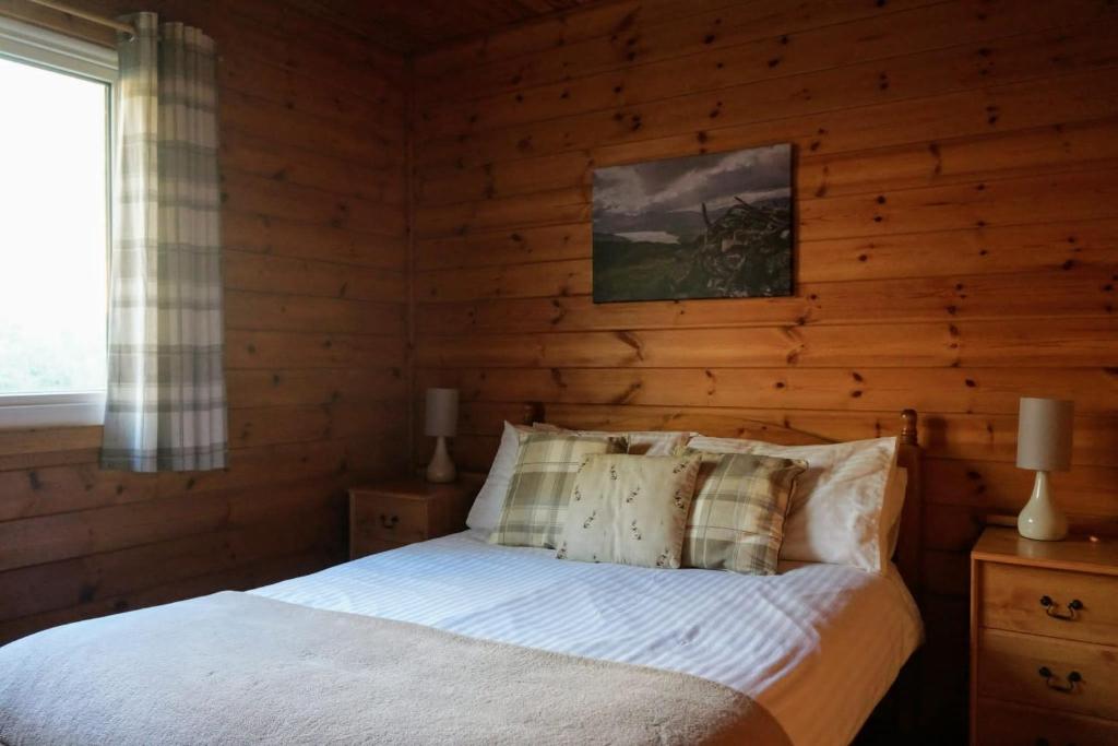 a bedroom with a bed with a wooden wall at Woodland Hazel Lodge in Killin