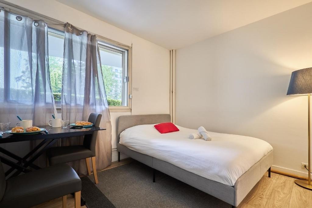 Cette petite chambre comprend un lit, un bureau et une fenêtre. dans l'établissement Le Marquis - T1 - 5 mins de la Cathédrale, à Reims